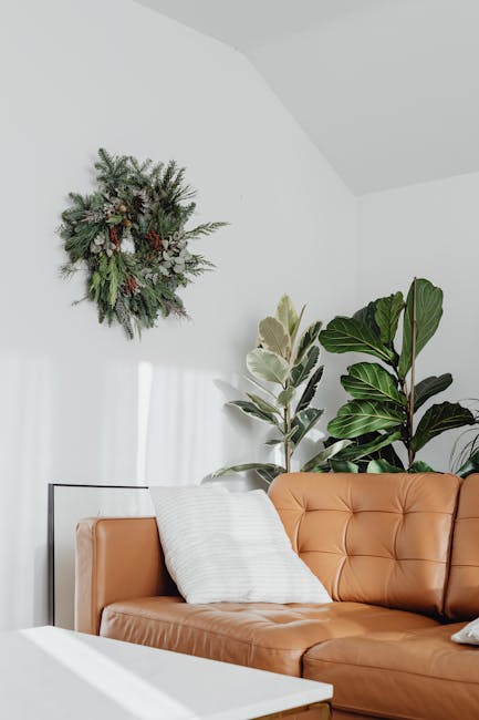 Stylish living room featuring a leather sofa, indoor plants, and a wall-mounted wreath for a fresh look.